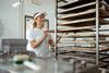 A young female baker putting sausage rolls onto a tray