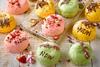 Green, pink, and yellow doughnuts topped with rose petals, chocolate, and dried strawberries