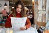 A woman in a red jumper looking at a menu in a nice restaurant
