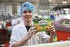 An employee holds up a box of Mr Kipling Bramley Apple pies at a production site.  2100x1400