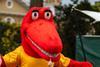 A young child offers a lollipop to a red dinosaur character wearing a Roald Dahl’s Marvellous Children’s Charity t-shirt