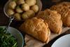 Cornish pasties on a board with potatoes and kale