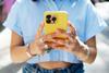 A young person using a phone with a yellow case