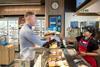 A staff member serves a customer at the newly opened Greggs shop at Sainsbury's petrol station in Cobham, Surrey