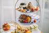 Afternoon tea stand laden with cakes, pastries, and scones