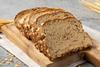 Sliced brown bread on a chopping board with wheat