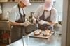 Two young bakers blowtorching meringue on top of a croissant