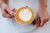 A pair of hands holding a mug with a lovely latte inside