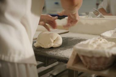 A baker at The Bread Factory's Hendon bakery shaping dough