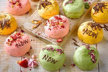 Green, pink, and yellow doughnuts topped with rose petals, chocolate, and dried strawberries