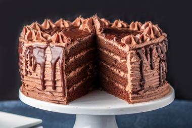 A decadent layered chocolate cake on a white cake stand