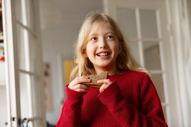 A blonde, long-haired child eating bread