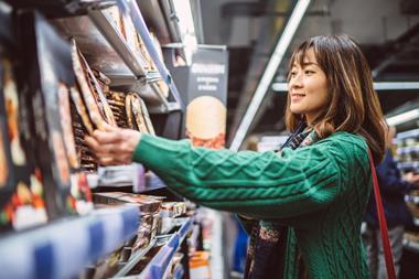 Young female shopper buying pizza in UK supermarket