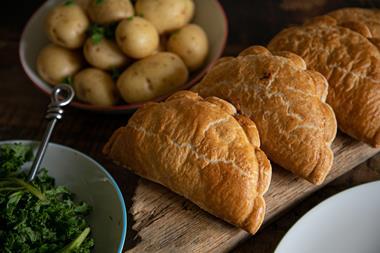 Cornish pasties on a board with potatoes and kale