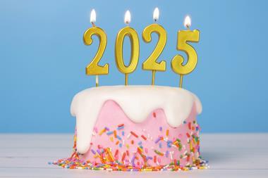 A pink cake with sprinkles on and 2025-shaped candles on top