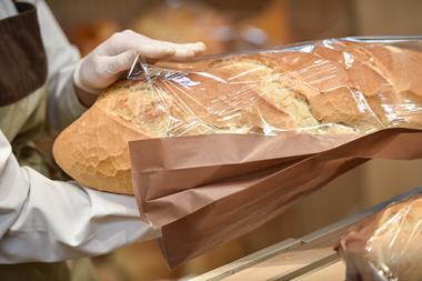A baker packaging a loaf of bread while wearing gloves