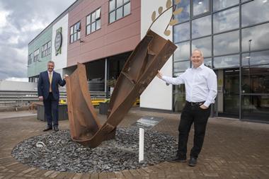 Mandy Jones - Jones Village Bakery CEO Simon Thorpe (right) stands with Cllr Nigel Williams by the  twisted metal girder placed in front of the company's headquarters in Wrexham as a reminder of the 2019 fire