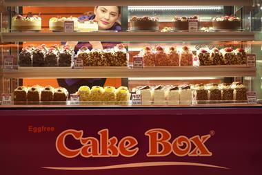 A staff member pulls out a cake from a display fridge at a Cake Box franchise  2100x1400