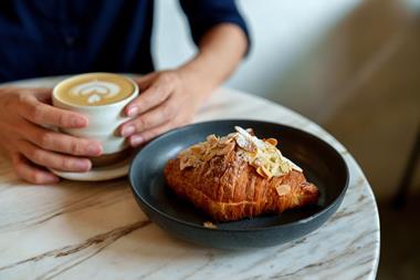 A woman enjoying a cup of coffee and an almond croissant