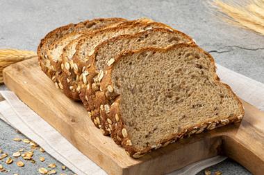 Sliced brown bread on a chopping board with wheat