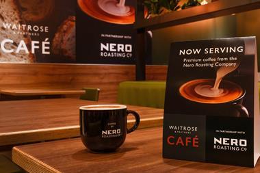 A coffee cup on a wooden table in a Waitrose and partners cafe