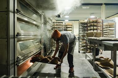 A staff member removes a tray of freshly-baked loaves out of an oven at Company Bakery's existing site in Devon Place, Edinburgh - Company Bakery