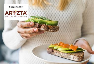 A woman in a white sweater eating avocado on toast