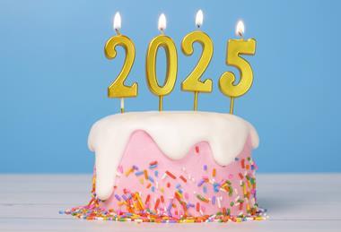 A pink cake with sprinkles on and 2025-shaped candles on top