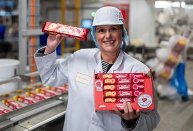 Rebecca Phillips, factory manager, FBC UK in a white coat and hairnet holding several packs of Jammie Dodgers