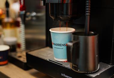 Fresh coffee being poured into a Warrens Bakery branded cup