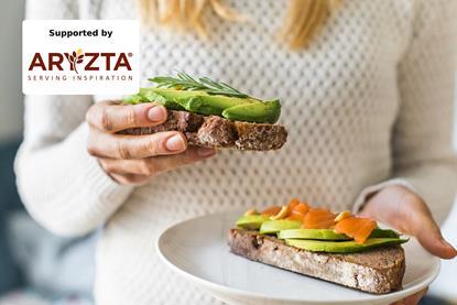A woman in a white sweater eating avocado on toast