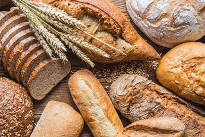 A selection of breads on a wooden surface withy wheat stalks