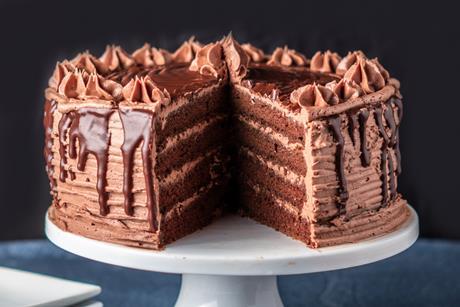 A decadent layered chocolate cake on a white cake stand