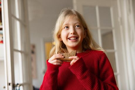 A blonde, long-haired child eating bread
