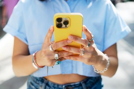 A young person using a phone with a yellow case