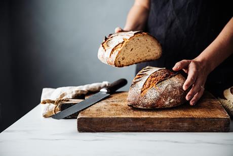 A baker slicing a sourdough loaf in half