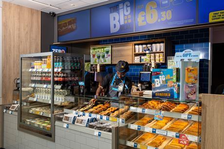 Greggs - A staff member arranges products behind a counter at a Bitesize Greggs outlet