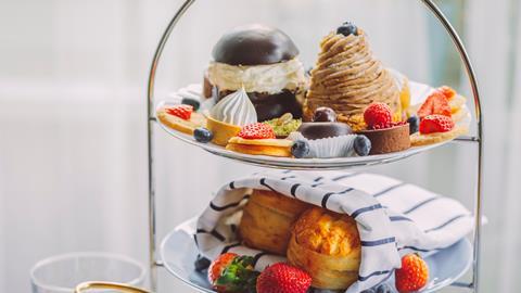 Afternoon tea stand laden with cakes, pastries, and scones