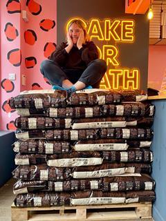 Cake or Death founder Katie Cross sits on a stack of chocolate sacks