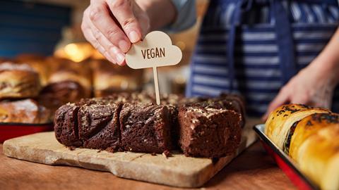 A vegan sign being placed in a slab of chocolate brownies