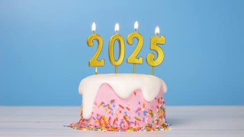 A pink cake with sprinkles on and 2025-shaped candles on top