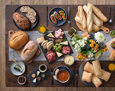 A selection of breads, meats, and cheeses on a lovely wooden table
