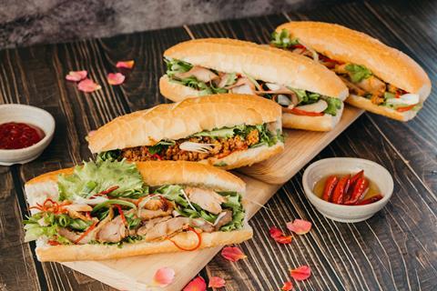 Four bahn mi filled with pork, lettuce, and other vegetables