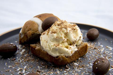 A hot cross bun with ice cream filling and mini chocolate eggs scattered around