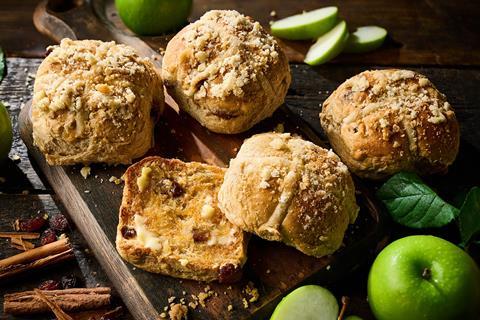 Co-op Apple Crumble Hot Cross Bun with apple and cinnamon sprinkled around it