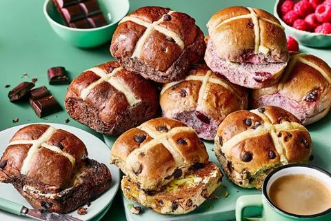 A selection of hot cross buns, toasted and topped with butter, on a green background