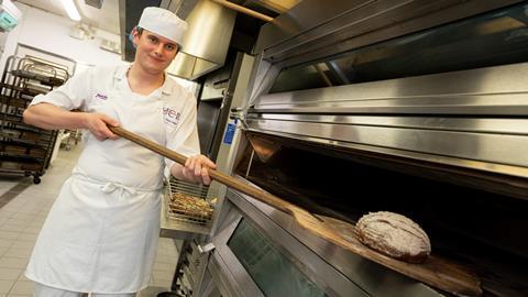 A student baker at UCB putting dough into an oven