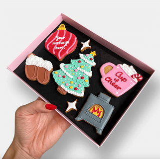 Beautifully iced Christmas cookies in the shape of a Christmas tree, bauble, fireplace, hot chocolate, and slippers