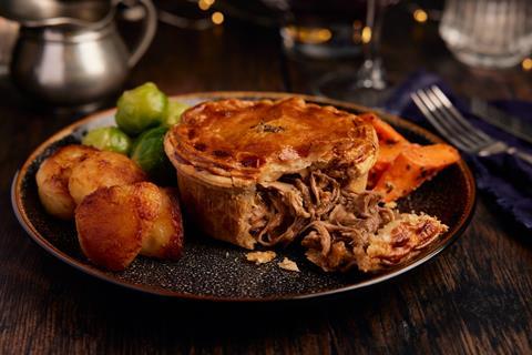 A Pork, Stuffing & Cranberry Pie on a plate with roast potatoes and Brussels sprouts