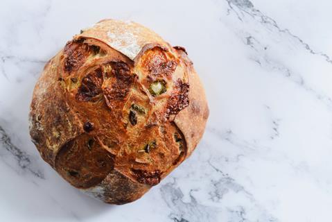 Whole loaf of Jalapeño cheddar sourdough bread on marble table